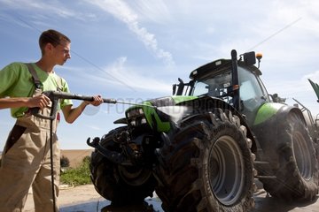 Junger Mitarbeiter reinigen einen Traktor mit einem Carsh