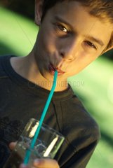 A boy drinking a glass of water with a straw