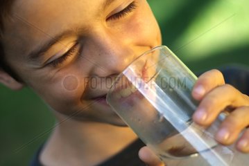 A boy drinking a glass of water with a straw