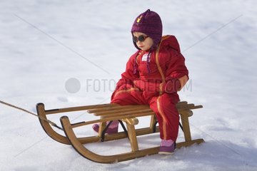 Happy girl sitting on a wooden sledge France