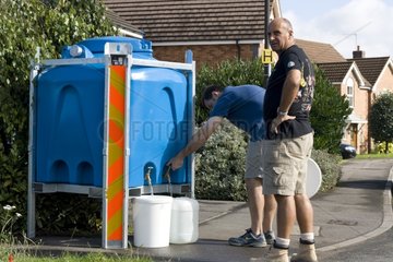 Two men filling cans of drinking water UK