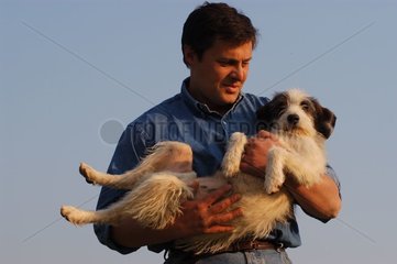 Mann  der seinen Hund in seinen Armen trägt
