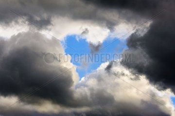Breakthrough sky blue heart shaped through clouds