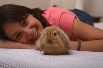 Young woman on a bed with a rabbit