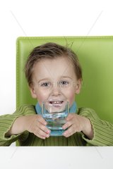 Boy sitting on a green chair holding a glass of water