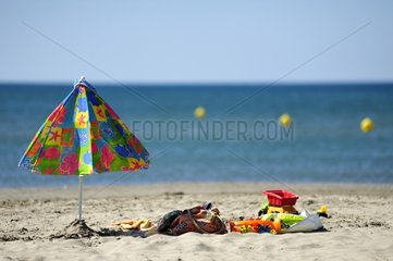 Parasol and colorful children's games on the beach