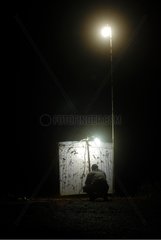 Man observing the contents of a light trap Guiana