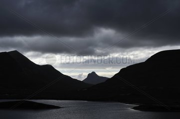 Loch and Stac Pollaidh mountain under cloudy sky Scotland
