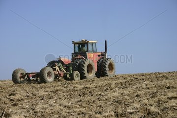 Tractor plowing a field between ground and sky France