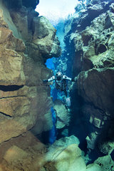 Diver submerges into Silfra Canyon  between the Eurasian and American tectonic plates. Silfra fissure is actually a crack between the North American and Eurasian continents that drift apart about 2cm per year. Thingvellir National Park  Iceland.