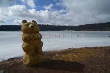 Holzskulptur des Bären am Rand eines kalten Sees Auvergne