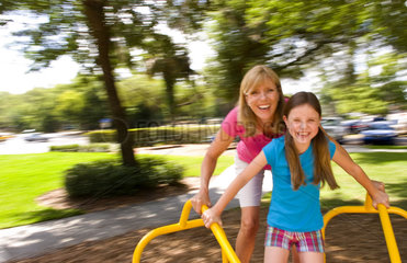 Mother and daughter having fun spinning on ride in playground