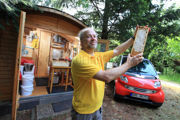 Urban Beekeeping - Ralf Schneider Rathmann  50 years old  owns forty hives in Berlin. This enthusiast is posing here in front of his main apiary set up in the Luisen-Friedhof cemetery in the Charlottenburg-Wilmersdorf neighborhood. In the background on the left is Ralf?s extraction cabin where all the machines work on solar energy. To the right  Ralf?s Smart car is devoted to beekeeping. ?Berlin is a very good place for beekeeping?  this plumber by profession tells us. ?I produce nearly 6 different monofloral honeys that I sell with my wife in the markets on weekends.? Germany