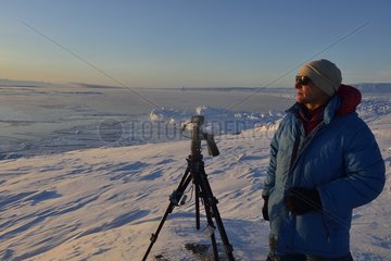 Explorer setting his camera for a timelaps of the Sun  Greenland  Februaury 2016  Scoresbysund Fjord