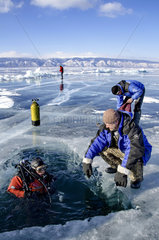 Diver in a hole cut in ice  Lake Baikal  Siberia  Russia