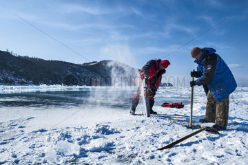 Cutting a hole in the ice before a dive - Lake Baikal  Siberia  Russia