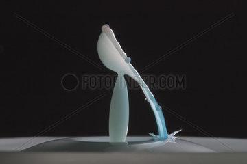 Drop of milk falling into milk on black background