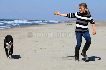 Girl playing with a Border Collie on a beach