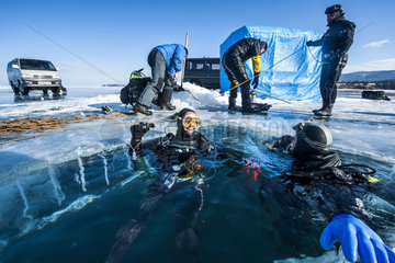Scuba divers returning from a dive under the ice  Lake Baikal  Siberia  Russia