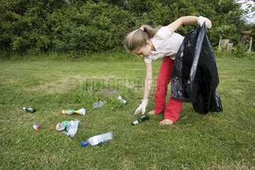 Young girl collecting discarded litter in a park UK