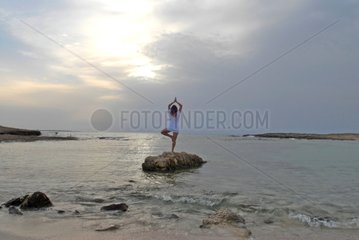 Mixed female in yoga position facing the sea Spain