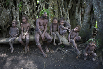 Man and children sitting on a roots - Tanna Vanuatu
