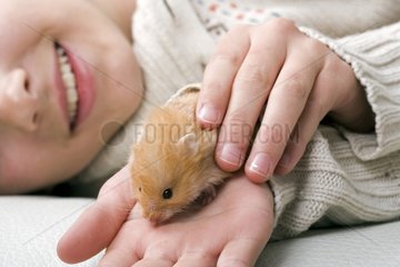 Girl laid down with a hamster in the hand France