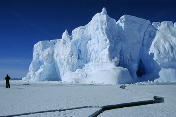 Man in front of an iceberg and fissures Antarctica