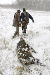 Jäger ziehen einen toten Wildschwein in Schnee Frankreich