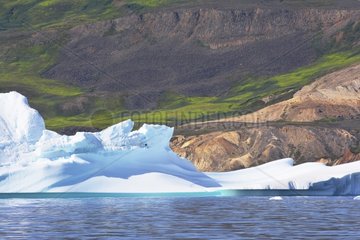 Denmark. Greenland. West coast. Iceberg in front of the landscape under erosion on the east coast of Disko island.