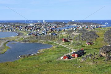 Denmark. Greenland. West coast. Disko Island. Houses of the village of Qeqertarsuaq with icebergs on the foreground.
