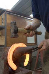 Blacksmith hammering a hot horseshoe France
