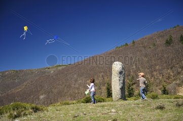 Children playing kite in front of a Menhir Cevennes France