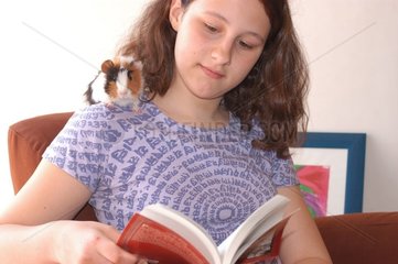 Adolescente lisant avec son cochon d'Inde tricolore