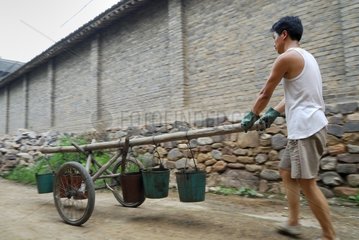 Transporting man of the buckets hung on a charette China