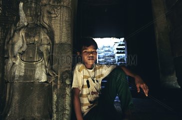 Ein Junge saÃŸ und lehnte sich gegen die Wand eines Tempels Kambodscha