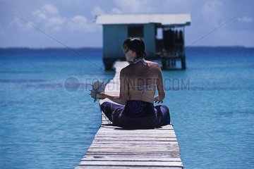 Young woman holding a shell sitting on a pontoon