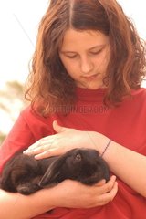 Adolescente caressant un lapin bélier noir