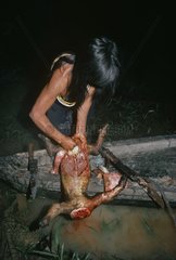 Matses woman preparing meat of a Two-Toed Tree Sloth Peru