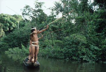 Matses Indians hunting in canoe in tropical forest Peru