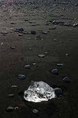 Ice block and pebbles on black sand Joekulsárlón Iceland