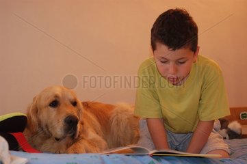 Enfant et golden retriever lisant sur un lit