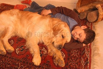 Enfant et golden retriever couchés sur un tapis persan
