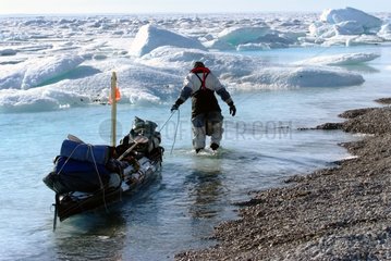 Man walk towing his kayak on the shore Arctic