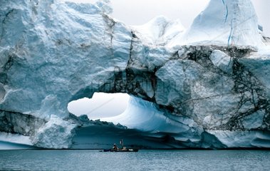 Kayak slipping in front of an iceberg Greenland