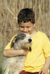 Garçon tenant dans ses bras un chien bâtard