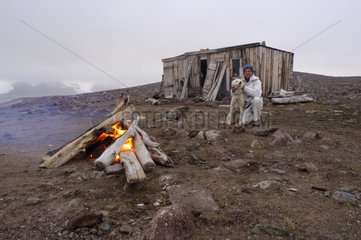 Man and dog in front of a campfire Shed of Raudenfjord