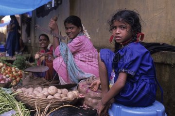 Young girl and her mother selling vegetables at the market