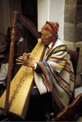 Sitted man playing of a traditional instrument Peru