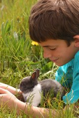 Enfant et lapin gris et blanc couchés dans l'herbe